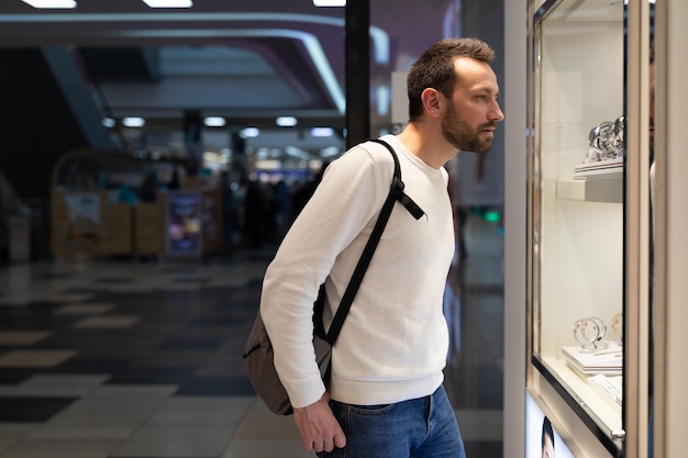 Photo of an adult doubtful thoughtful thinking handsome brunette man in a white sweatshirt and with