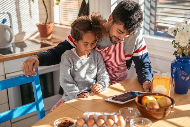 Photo of an african american father and daughter reading a recipe