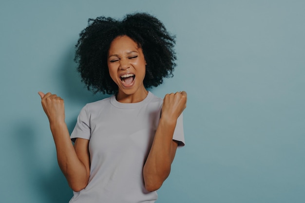 Photo of african american girl wears casual outfit on blue studio background