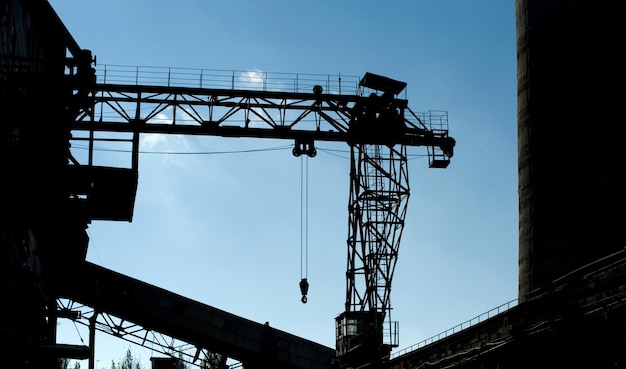 Photo after a hard large construction crane against the sky