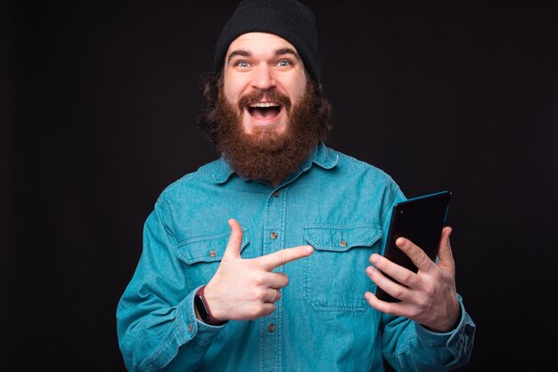 Photo of amazed bearded hipster man pointing at tablet