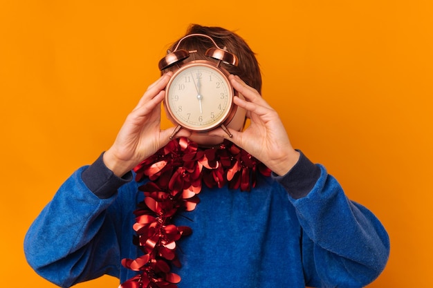 Foto foto di un ragazzino sbalordito che mostra l'orologio della sveglia ed è pronto per il new year