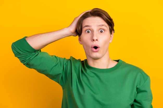 Photo of amazed young man open mouth touch head unbelievable information isolated on shine color background