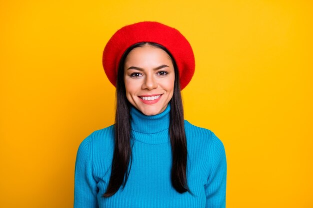 驚くべきラテン旅行者の女の子の写真歯を見せる晴れやかな笑顔スタイリッシュな外観着用モダンな赤いベレー帽帽子青いタートルネックジャンパー分離された明るい黄色の色の壁