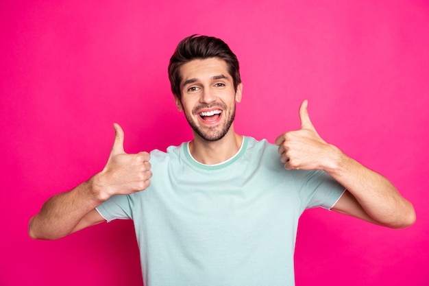 Photo of amazing macho guy revealing perfect white teeth raising thumbs up advising good dentist wear casual t-shirt isolated vibrant pink color background