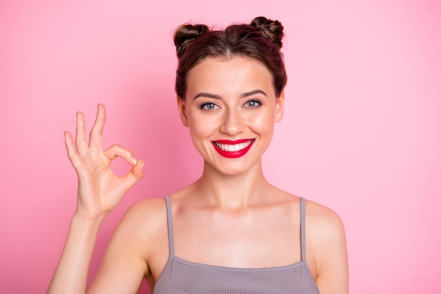 Photo of amazing youngster girl pretty buns red lips showing okay symbol expressing agreement good job wear casual grey tank-top isolated pink color