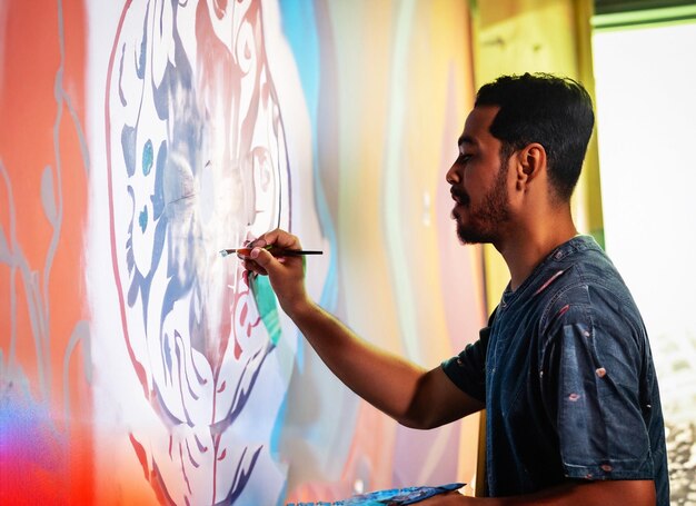 Photo of an artist is drawing a mural on the wall