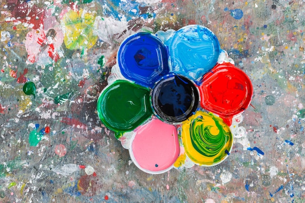 Photo of a artists palette loaded with various colour paints on the wood table background