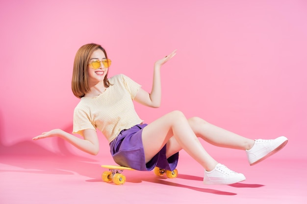 Photo photo of asian teenager girl with skateboard on pink background