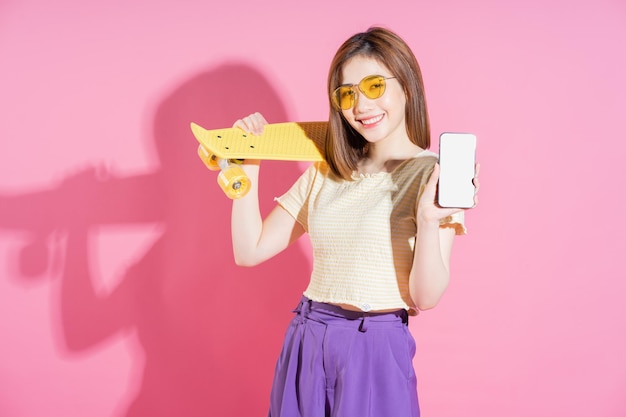 Photo photo of asian teenager girl with skateboard on pink background