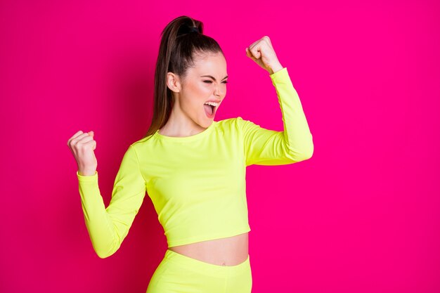 Photo of astonished pretty young woman stand fists up yell dress sport suit isolated on vibrant shine pink color background