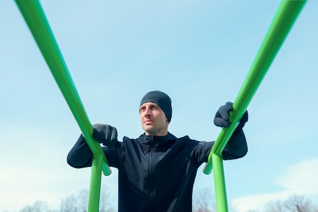 Photo of athlete pulling up on green horizontal bar