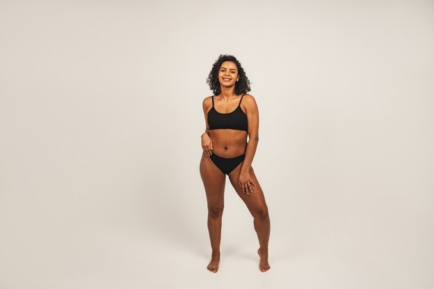 Photo of attractive black woman wears black underwear. Isolated over white background.