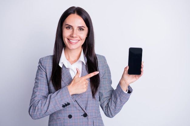 Foto di attraente donna d'affari tenere telefono gadget dispositivo app regia sensore dito schermo incredibile nuova interfaccia qualità formale abito scozzese isolato colore grigio sfondo