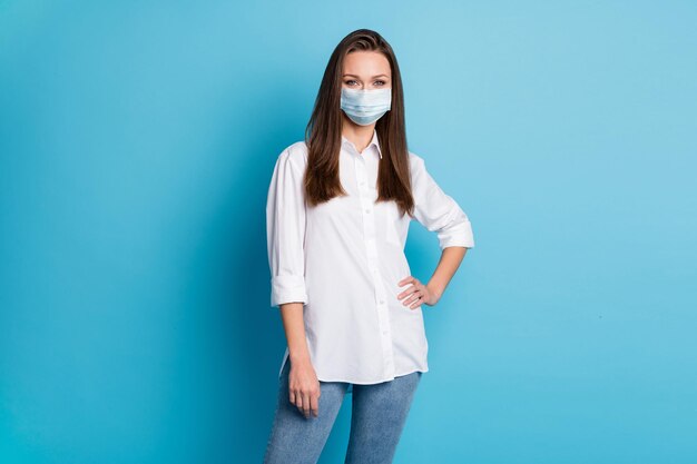 Foto di una donna d'affari attraente, acconciatura lunga, persona sicura di sé, indossa un respiratore, camicia bianca, jeans, isolato, colore blu, fondo