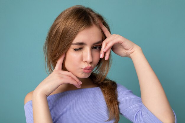 Photo of attractive cute happy emotional young woman poising isolated on background wall with free space wearing trendy casual clothes.