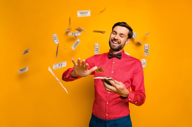 Photo of attractive elegant funny guy hold fan money bucks spending jackpot throwing away money falling wear trendy red shirt bow tie clothes 