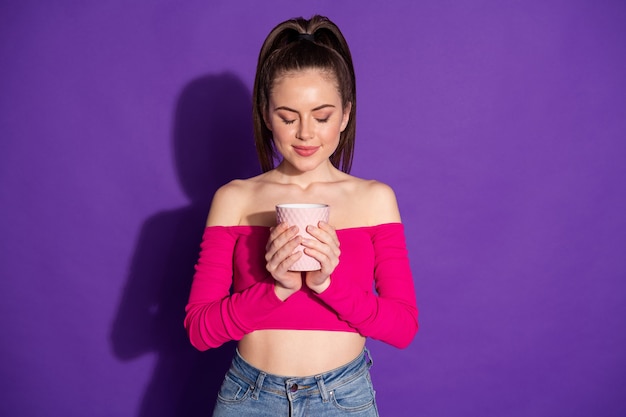 Photo of attractive girl hands hold mug closed eyes imagining wear pink uncovered shoulders top isolated violet color background