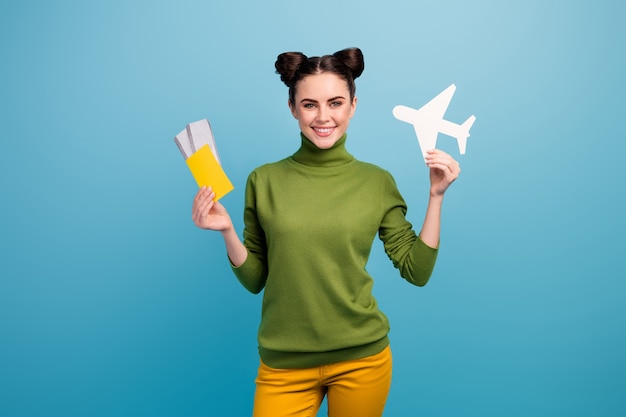 Photo of attractive lady hold paper air plane passport tickets advising flying way of traveling addicted traveler wear green turtleneck yellow trousers isolated blue color wall