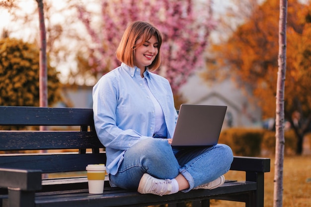 Photo of attractive lady student sit on bench in green park browsing notebook chatting friends