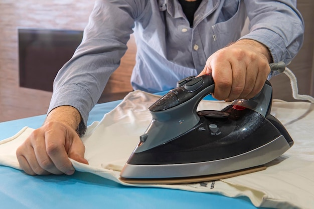 Photo of an attractive male ironing a shirt