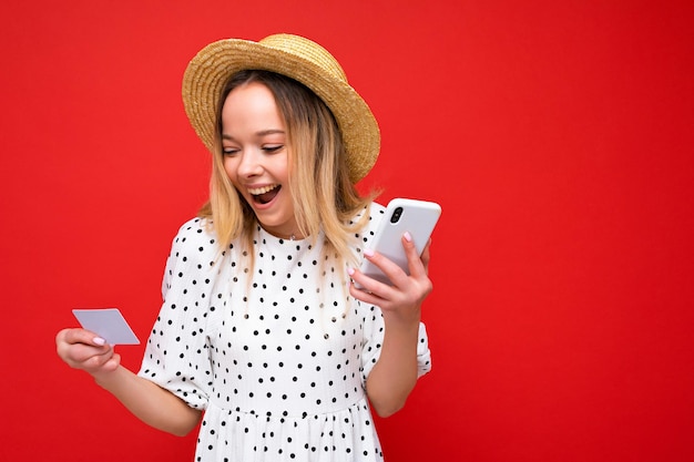 Photo of attractive positive surprised young blonde woman in summer clothes using cellphone and