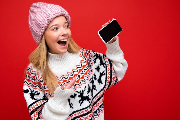 Photo of attractive smiling young blonde woman wearing warm knitted hat and winter warm sweater