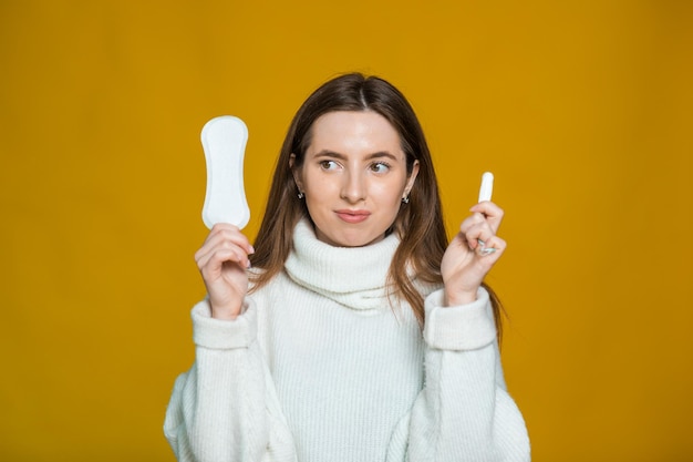 魅力的な女性の写真は綿のタンポンを持っており、衛生的なナプキンは驚きの表情をしています