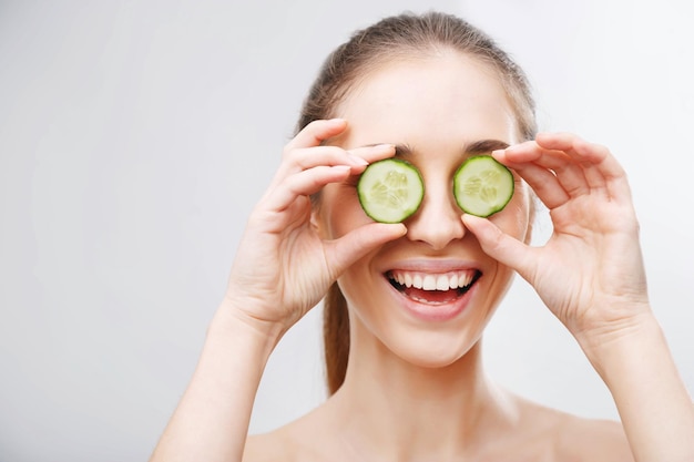 Photo of attractive young woman covering her eyes with cucumber