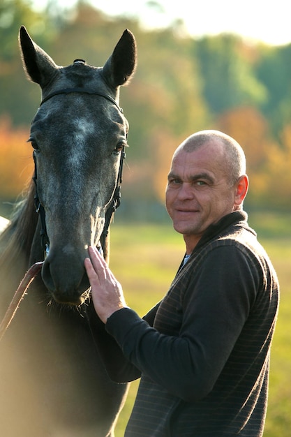 写真ハゲ男が野原で馬と一緒に歩く