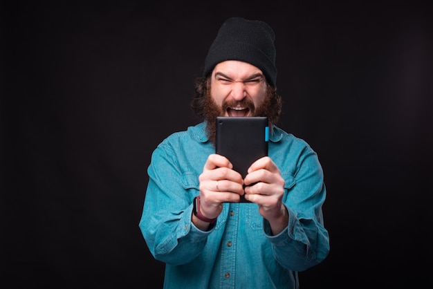 Photo of bearded man looking at tablet and nervous screaming