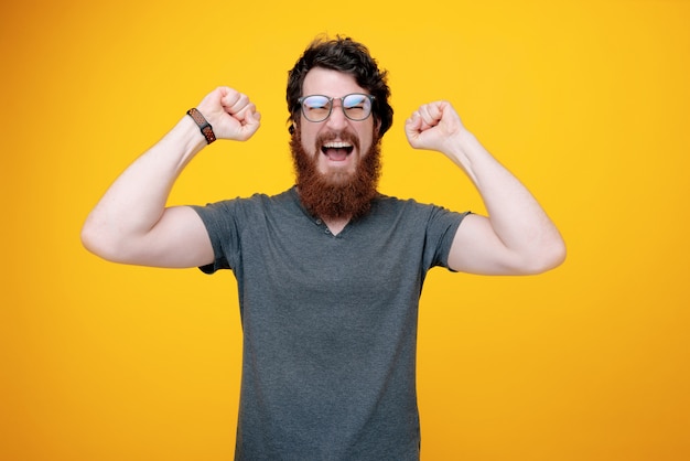 Photo of a bearded winner, handsome man screaming and celebrating with rised hands