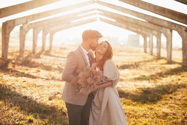 Foto di bella coppia, sposo che bacia moglie all'aperto al tramonto