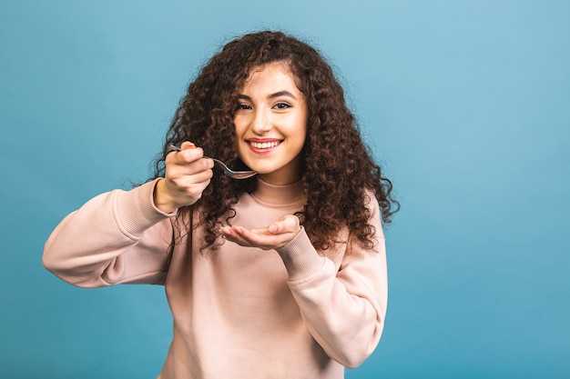 Photo of beautiful curly lady holding metal spoon in mouth look up empty space dreaming about tasty food isolated blue background.