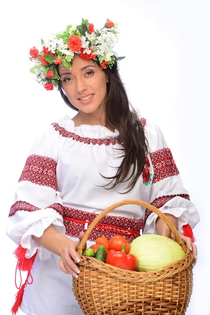 Photo of a beautiful and cute woman in Ukrainian costume with basket of vegetables