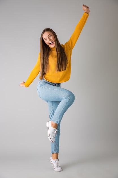 Photo of a beautiful excited young happy woman isolated over grey wall .