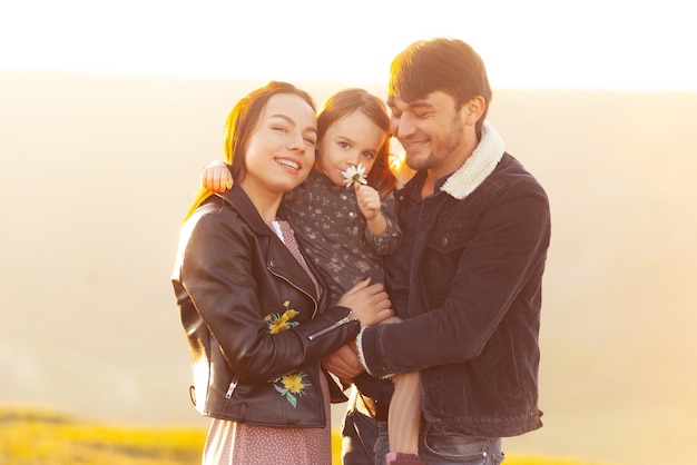 Foto di bella famiglia divertendosi all'aperto e abbracciando durante il tramonto