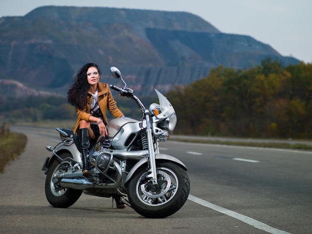 道路と自然の背景にバイクで美しい少女の写真