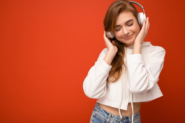 Photo of beautiful happy smiling young blonde woman wearing white hoodie isolated over colourful