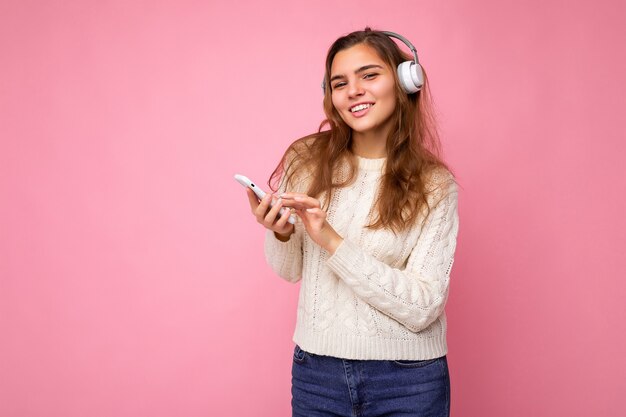 上に隔離されたスタイリッシュなカジュアルな服を着て美しいうれしそうな笑顔の若い女性の写真