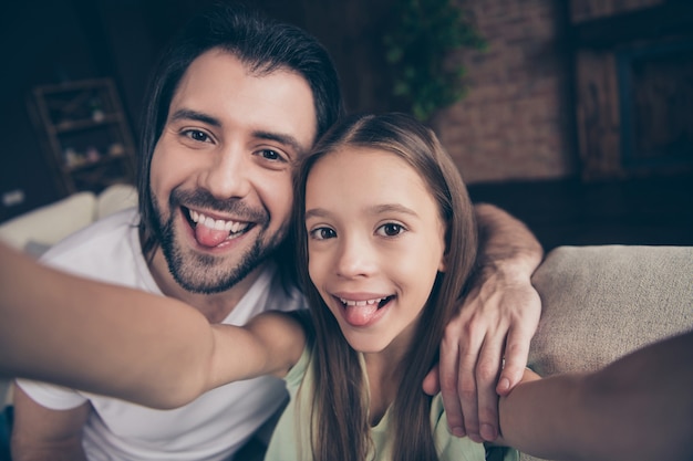 Photo of beautiful little adorable girl and handsome young daddy sit on comfy sofa