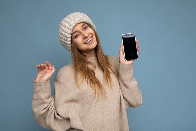 Foto di bella giovane donna di bell'aspetto positiva che indossa un maglione beige alla moda e maglia beige