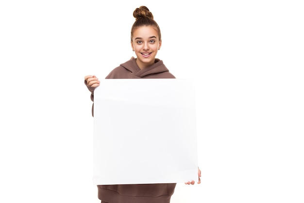 Photo of a beautiful positive smiling cute girl with dark hair and a bun in a brown hoodie with hood