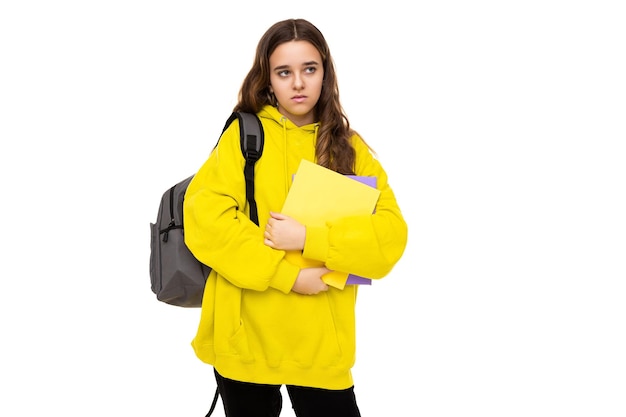 Photo of beautiful sad angry brunette teenage girl in stylish yellow sports hoodie with gray