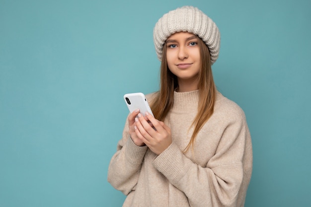 Foto di una bellissima giovane donna bionda seria che indossa un maglione caldo beige alla moda e un inverno lavorato a maglia