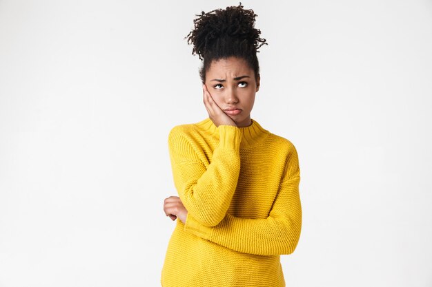 Photo of a beautiful young african confused woman posing over white wall.