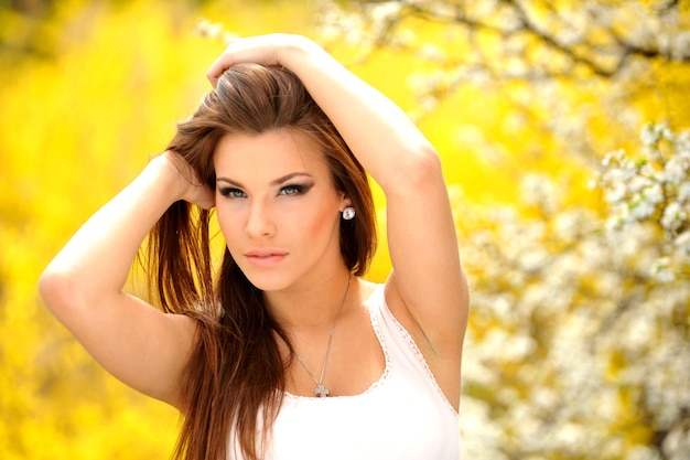 Photo of beautiful young girl on the nature of the model near the bright flowering trees