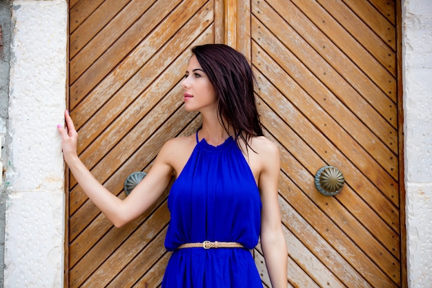 photo of beautiful young woman standing near the wooden old door in Greece