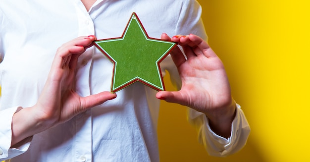 Photo of beautiful young woman with star shaped toy on the yellow