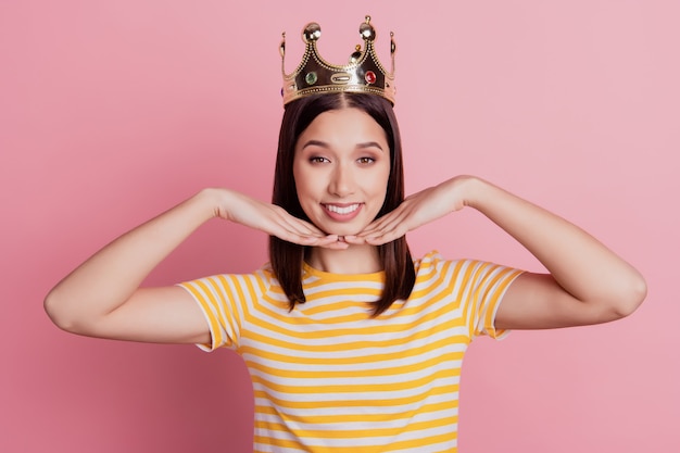 Foto foto di bellezza adorabile donna tenera mani mento sorriso raggiante a trentadue denti indossa una corona su sfondo rosa